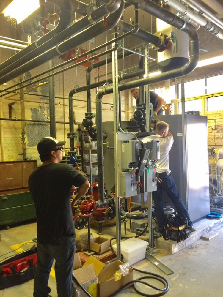 Two men are working on a machine in a factory