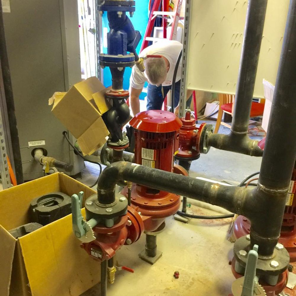 A man stands in a room surrounded by pipes and valves