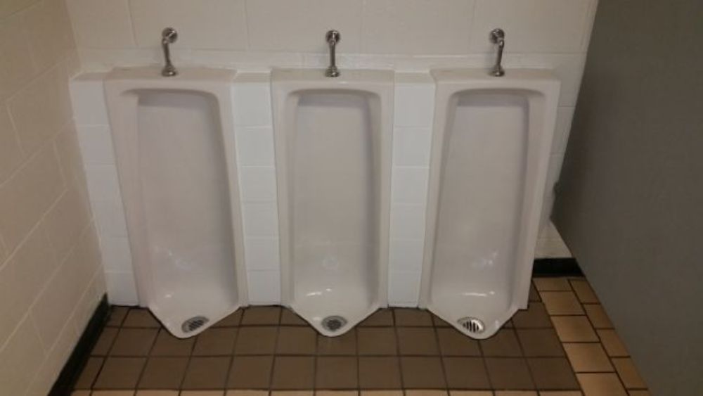 Three urinals are lined up next to each other in a public restroom.