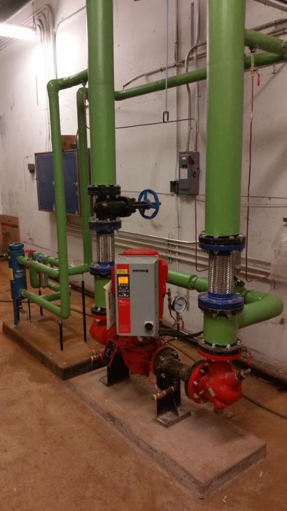 A room filled with green pipes and red valves.