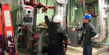 Two men are working on a machine in a factory.