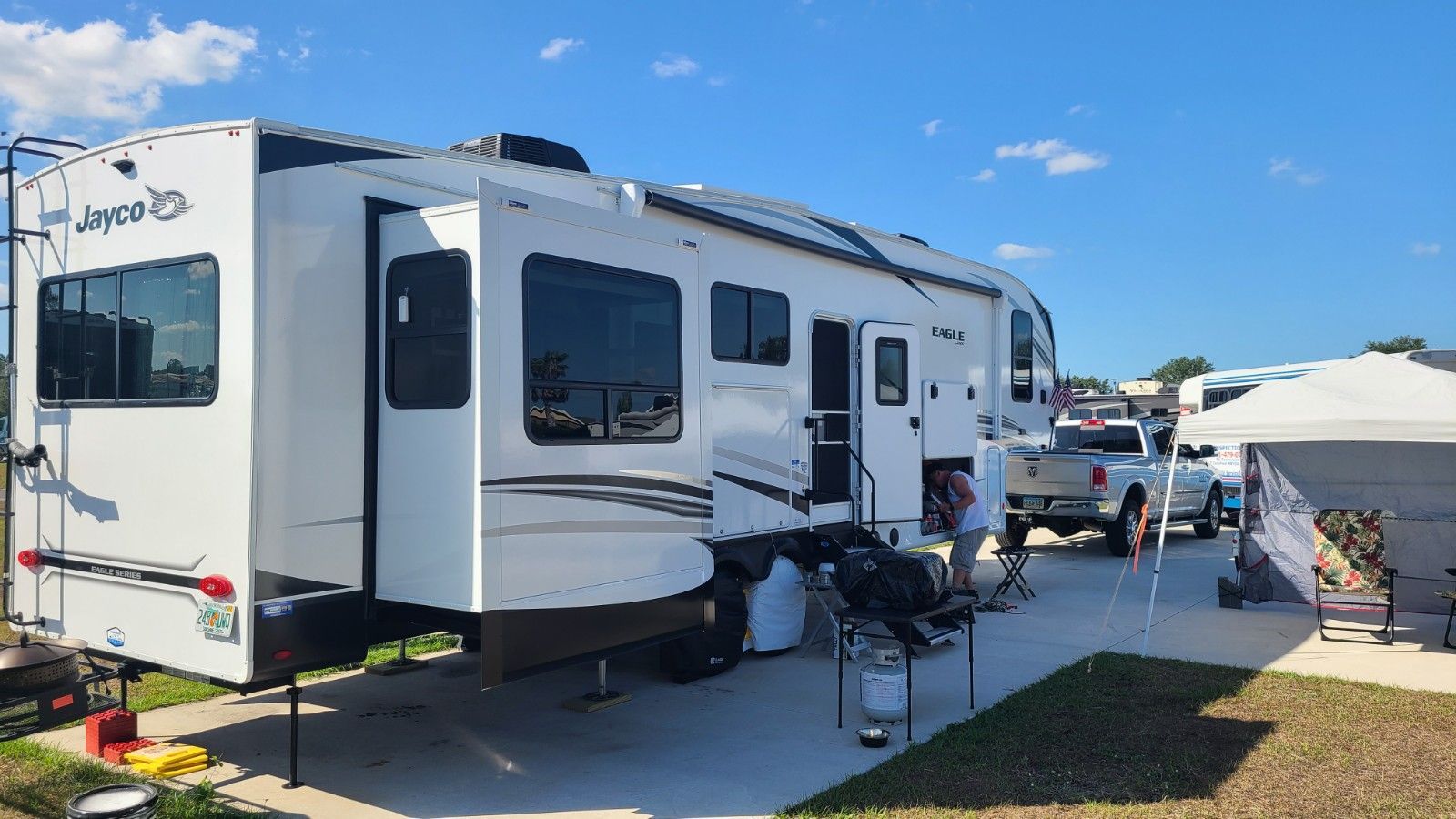 A white rv is parked in a parking lot next to a tent.