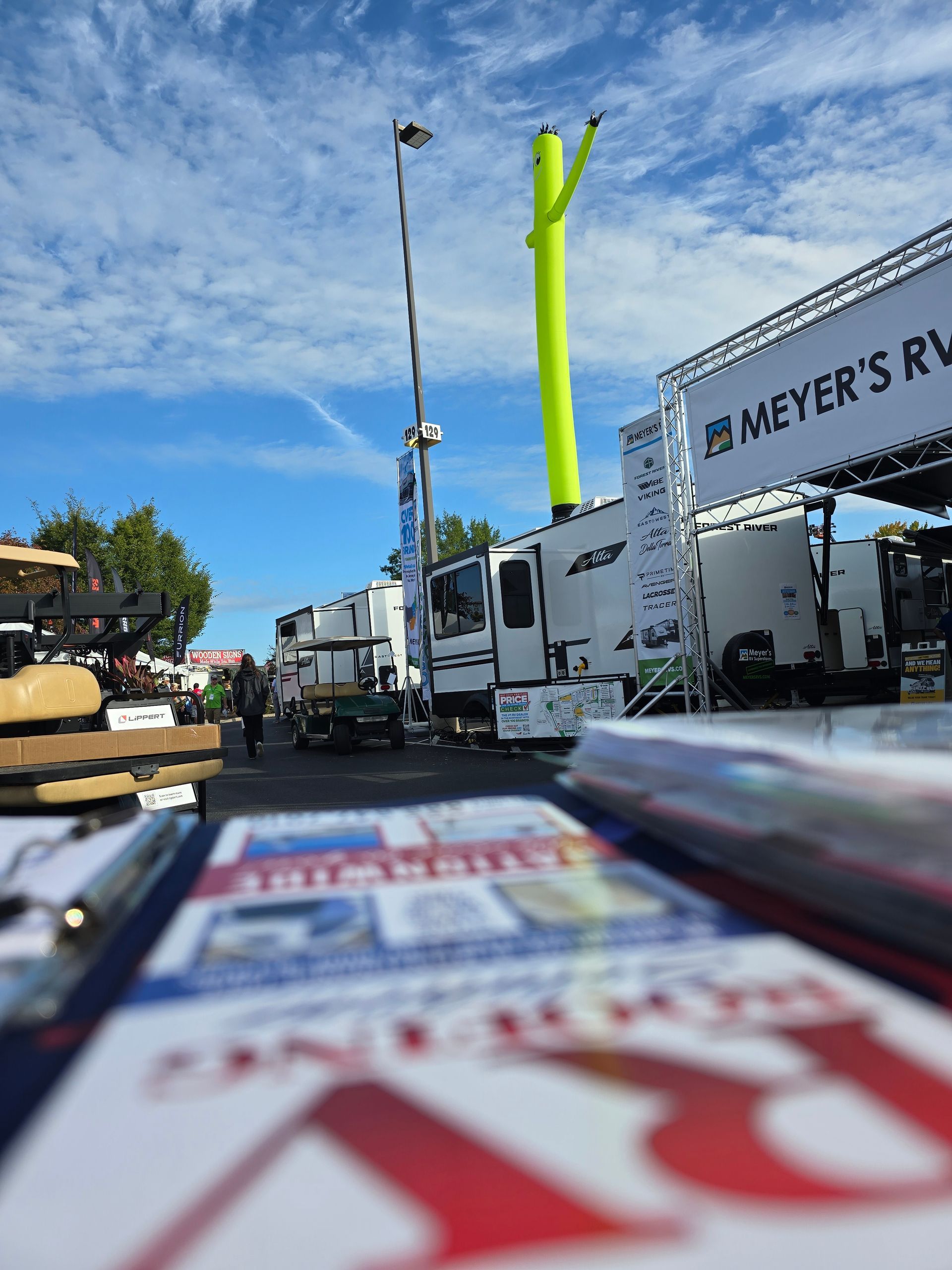 RV Show at Hershey PA with RV's, tall neon green inflatable tube, and blue sky.