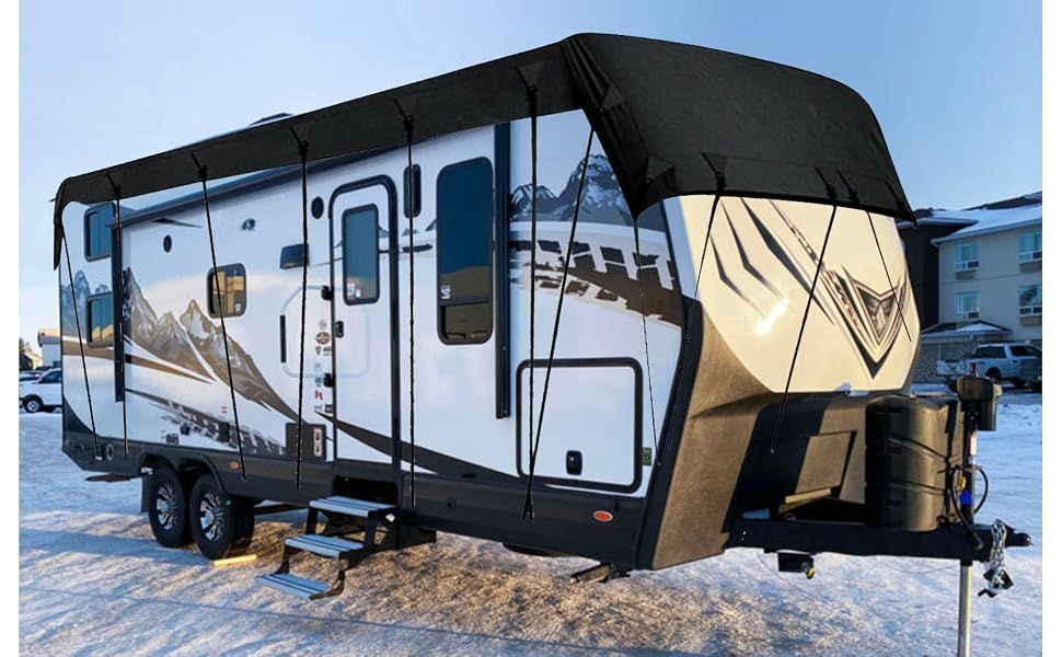 Large beige and black travel trailer parked in a snowy lot.
