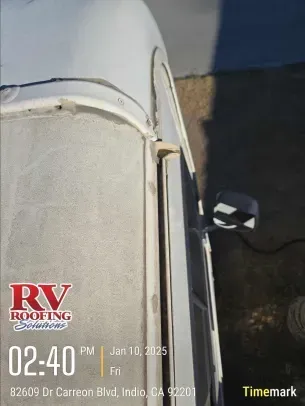 Overhead view of an RV, focusing on the roof and door, showcasing potential roofing work. A timestamp and logo are overlaid.