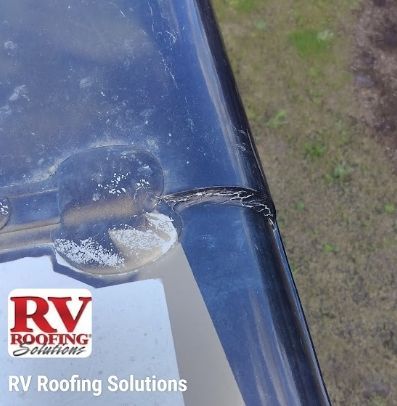 Damaged blue RV roof seam with peeling sealant and crack near a corner label for RV Roofing Solutions