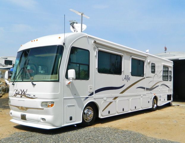 A large white rv is parked in a gravel lot