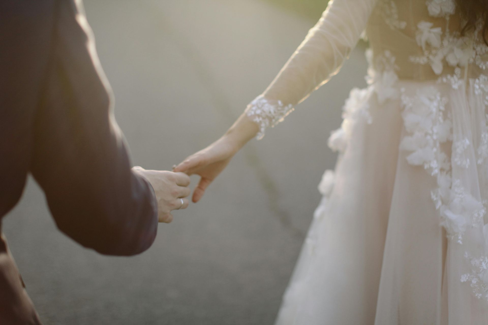 A bride and groom are holding hands on their wedding day.