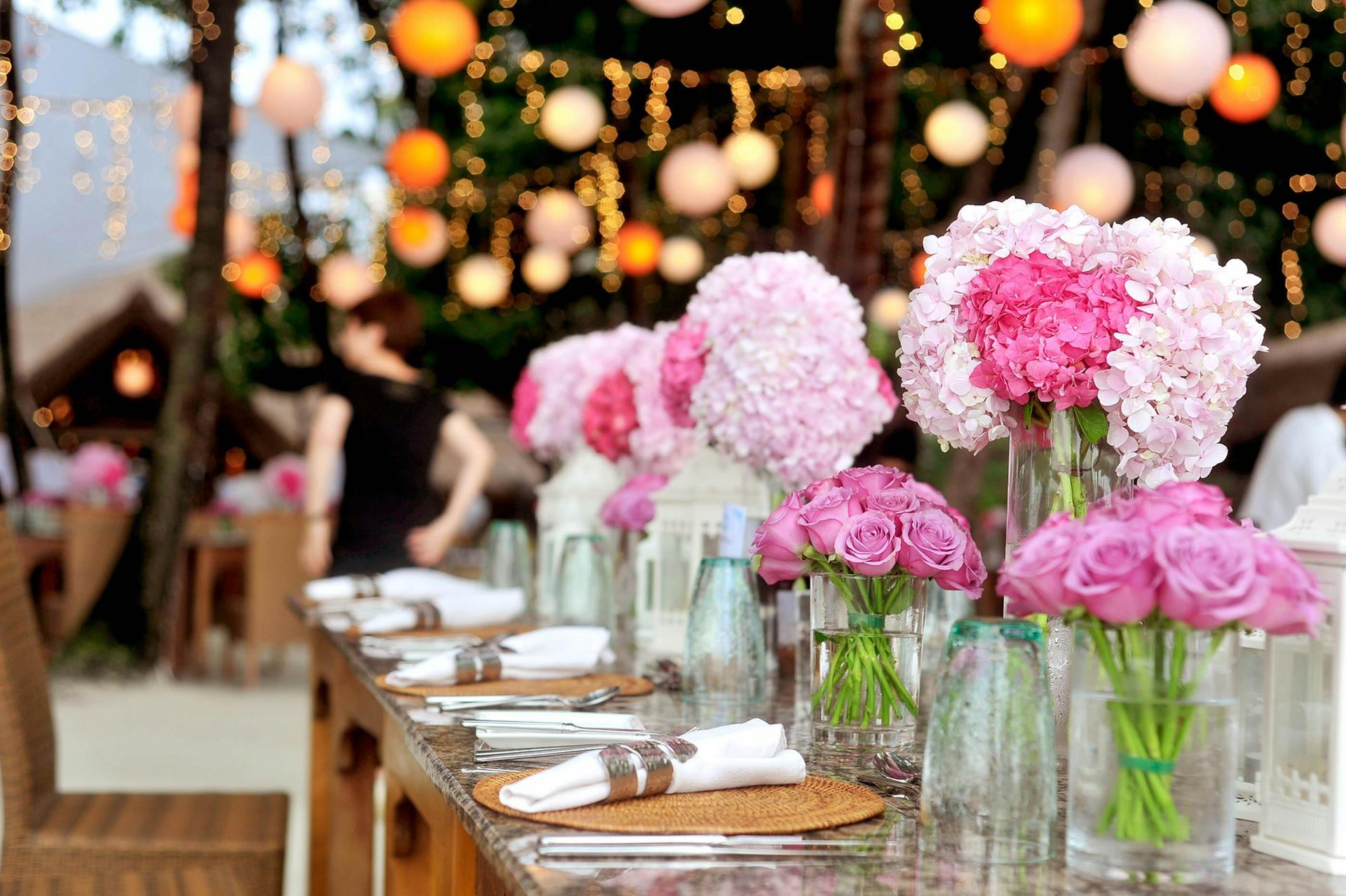 A long table set for a wedding reception with pink and white flowers in vases.