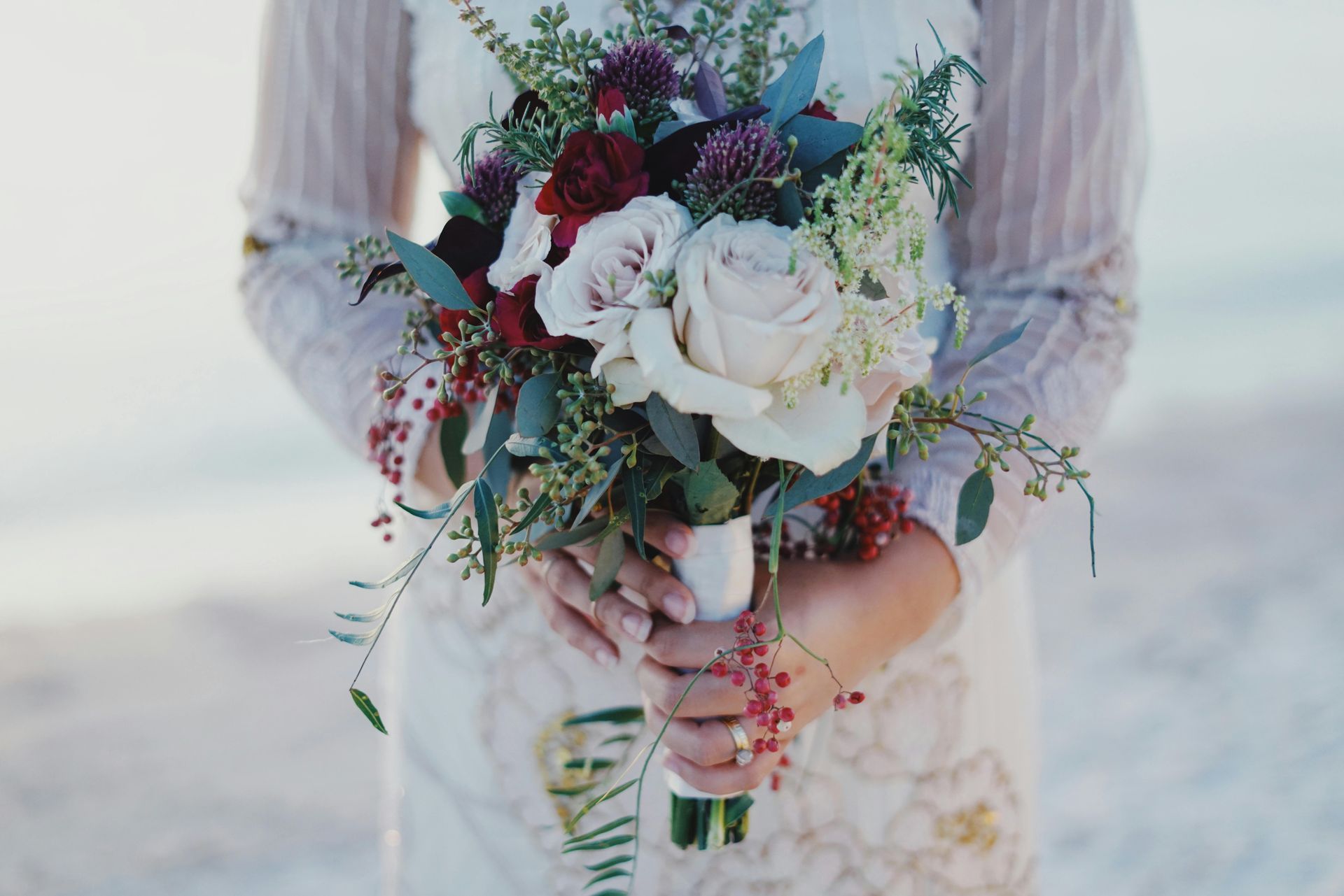 A bride is holding a bouquet of flowers in her hands.