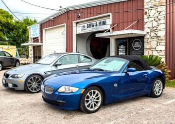 Two blue cars are parked in front of a building.