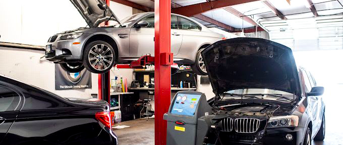 A car is sitting on a lift in a garage with the hood open.