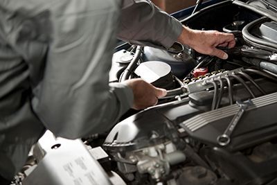 A man is working on the engine of a car.