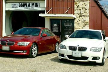 Two cars are parked in front of a bmw and mini garage.
