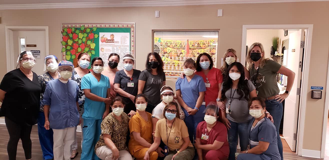 A group of people in a building pose for a photo, most wearing masks.
