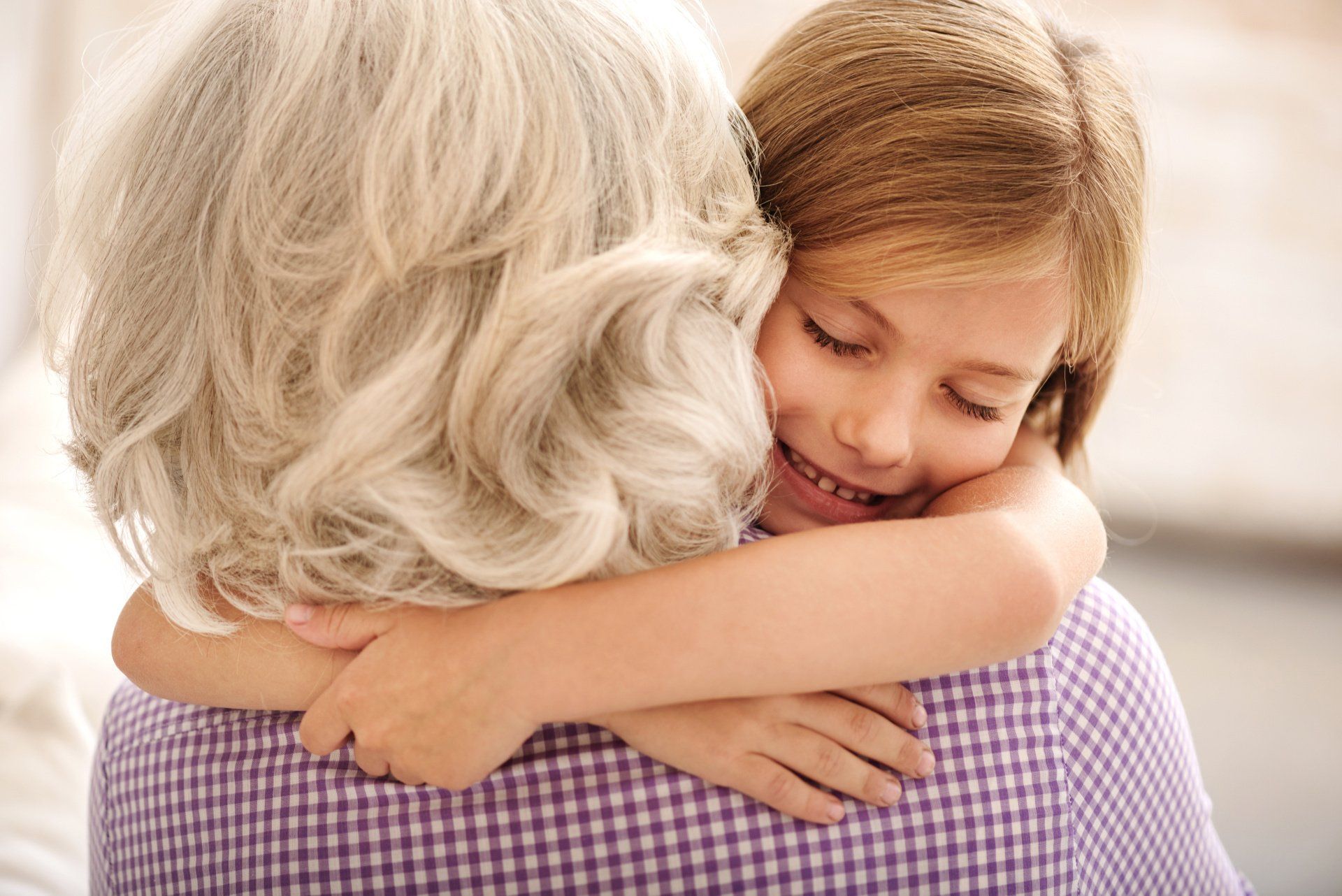 Young girl smiling, hugging an older woman with gray hair.