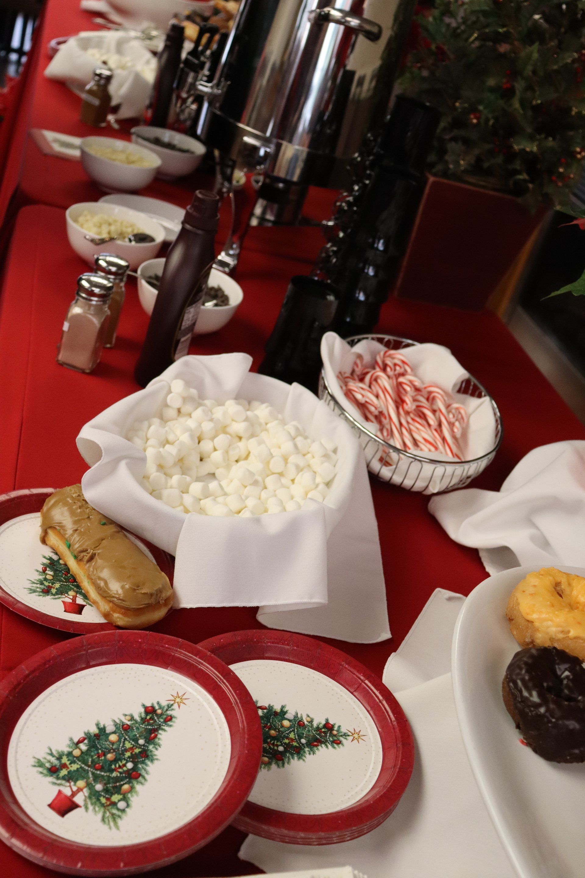 Christmas dessert table with plates, marshmallows, candy canes, and doughnuts.
