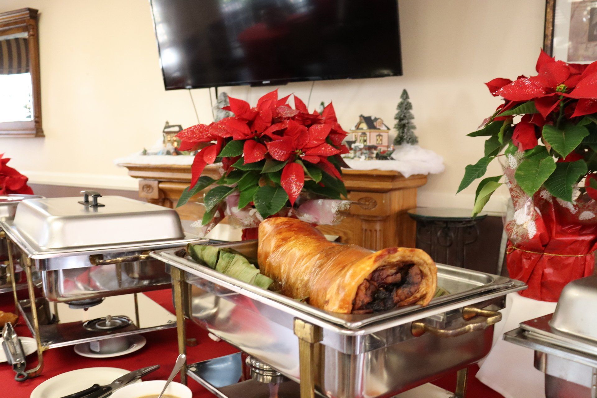 Buffet table with roasted pork and poinsettias; a festive holiday meal.