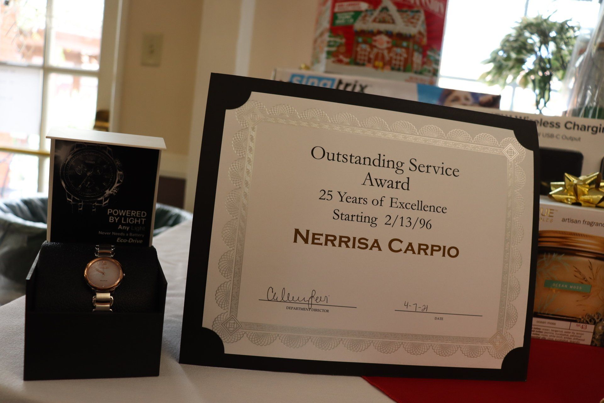 Award for Nerrisa Carpio, 25 years of service, with a watch in a box, on a decorated table.