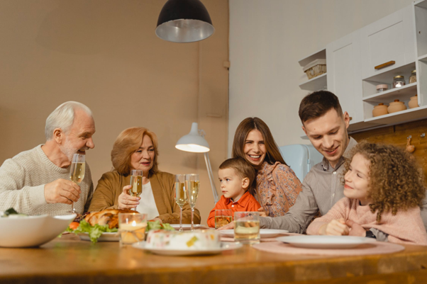 Family gathered around a table, toasting with champagne; smiles, warm tones, lit by overhead lights.