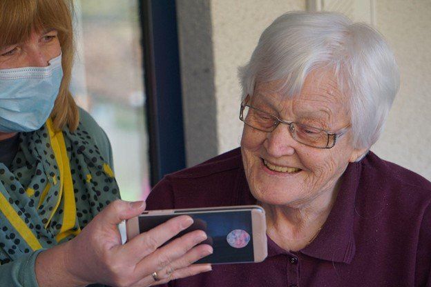 daughter bonding with senior mother over something on phone