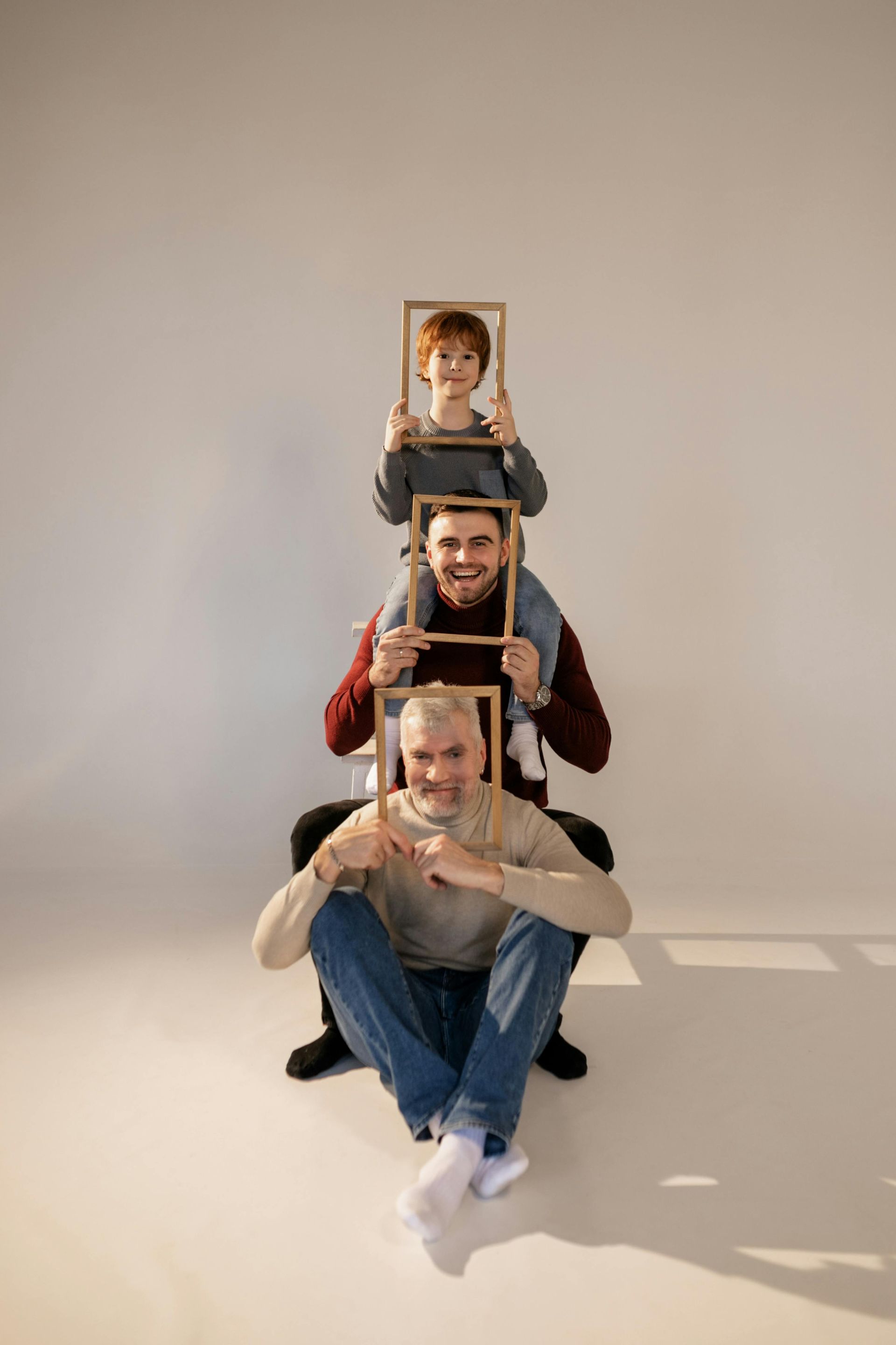 Four people in a row, holding frames around their faces.