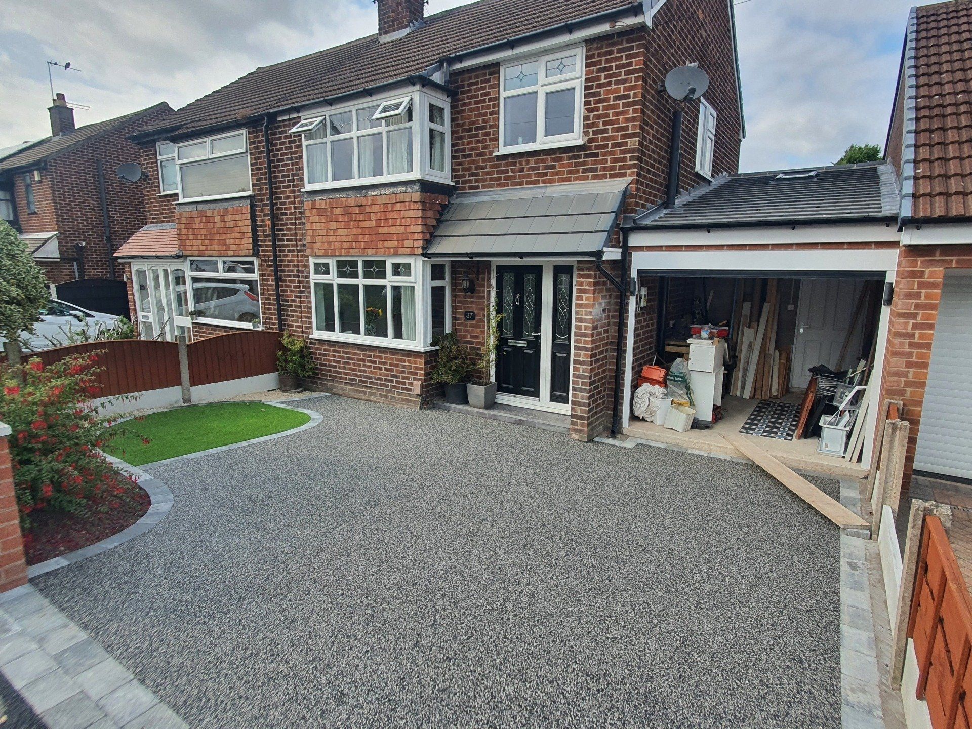 Brick house with gravel driveway, small lawn, and attached garage.