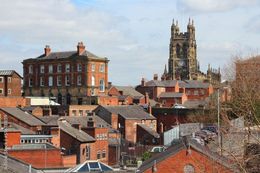 View of red brick buildings and church tower under a blue sky.