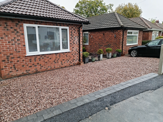 Red brick bungalows with gravel driveways and a black car parked in the driveway.