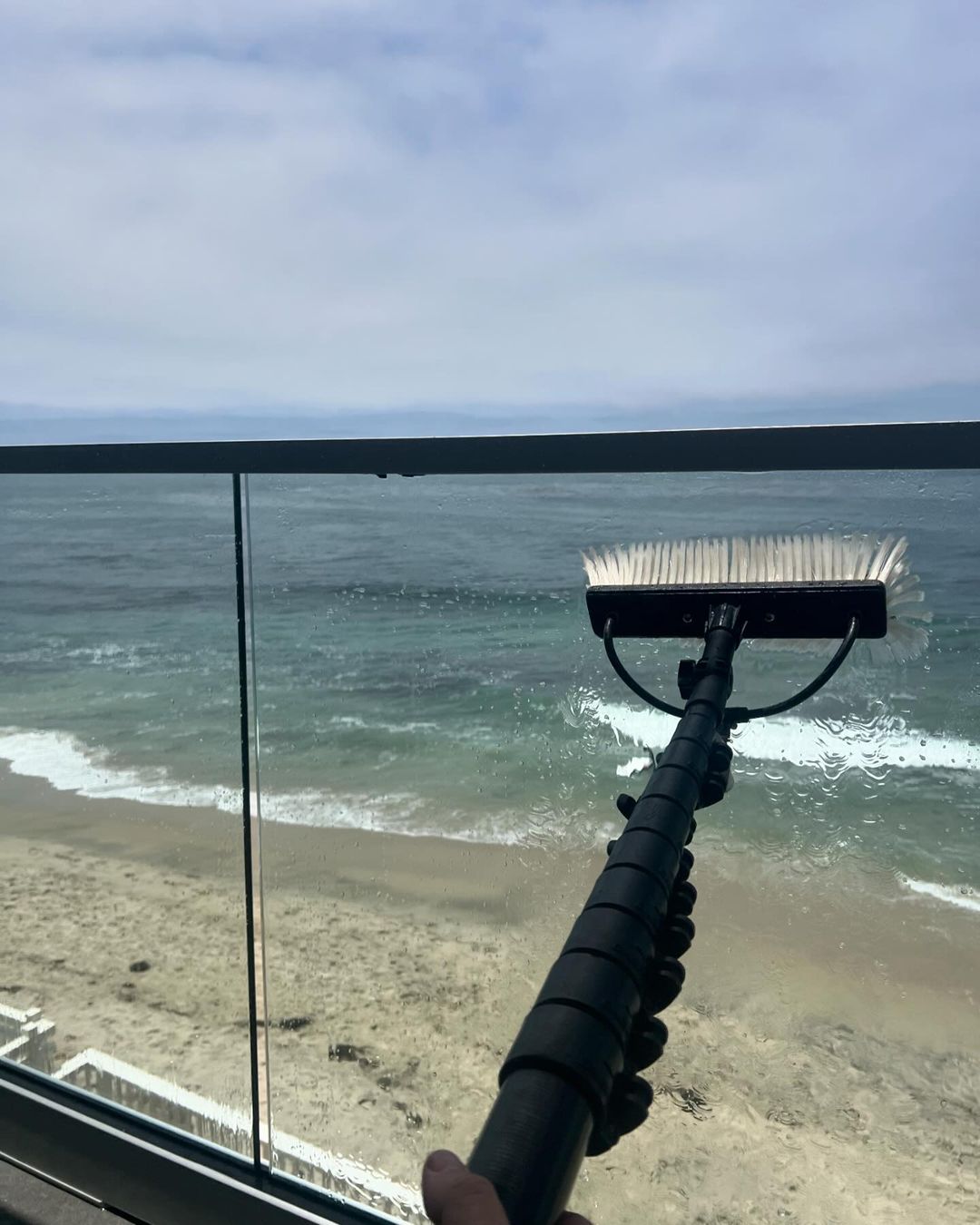 Snow brush on a vehicle overlooking a snowy beach and choppy water under a cloudy sky
