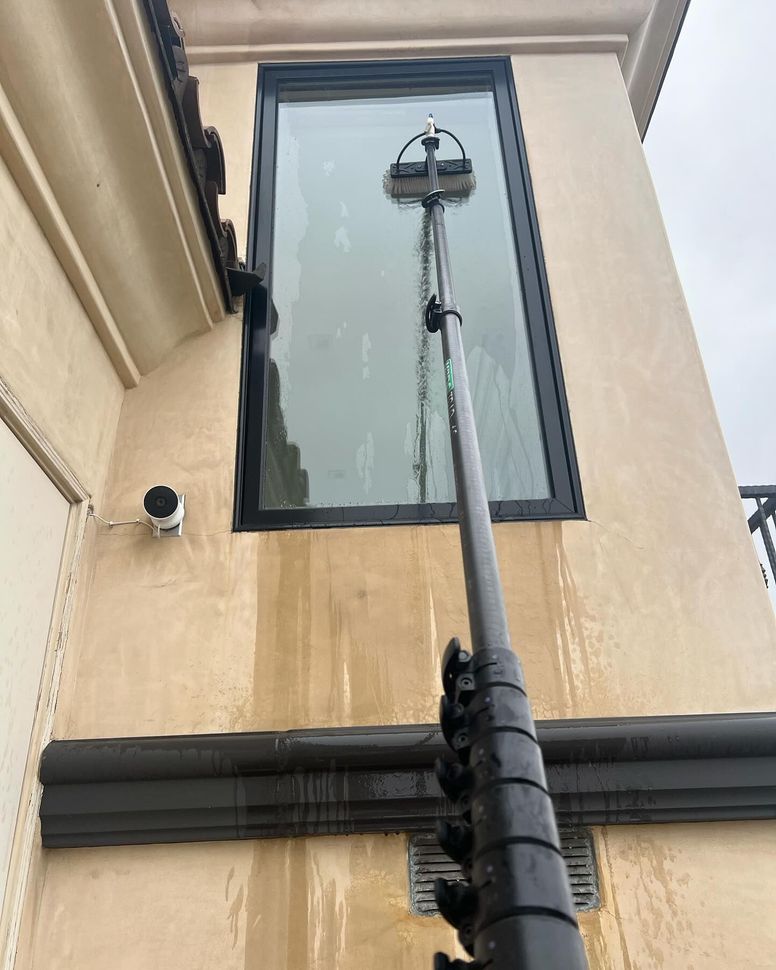 Tall building wall with a vertical utility pole and cables beside a window