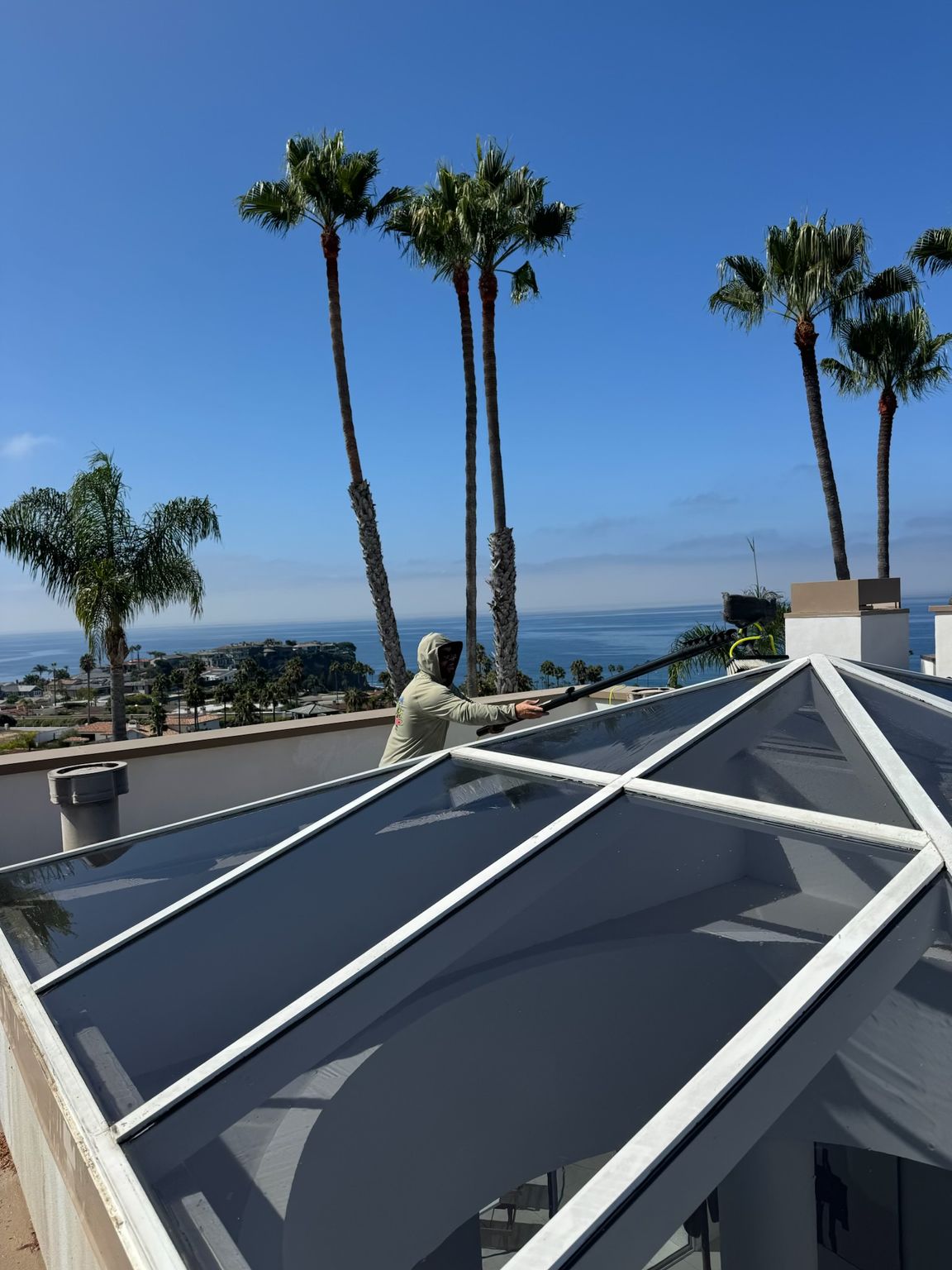 Rooftop with solar panels overlooking the ocean, palm trees, and a clear blue sky
