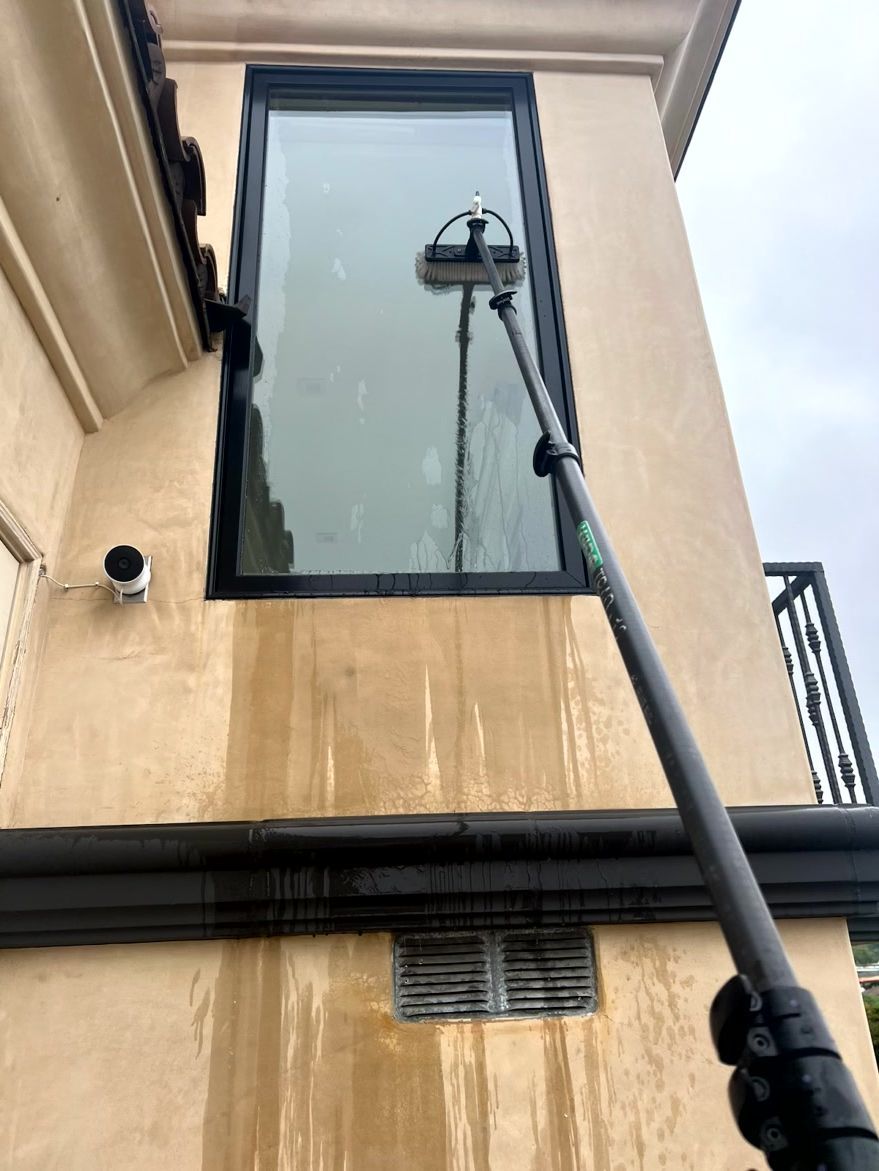 Streetlight on a pole reaching up beside a beige building with a large window and water stains on the wall