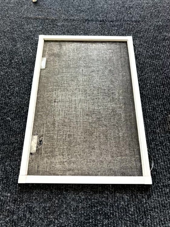 White mesh window screen frame on dark carpet background