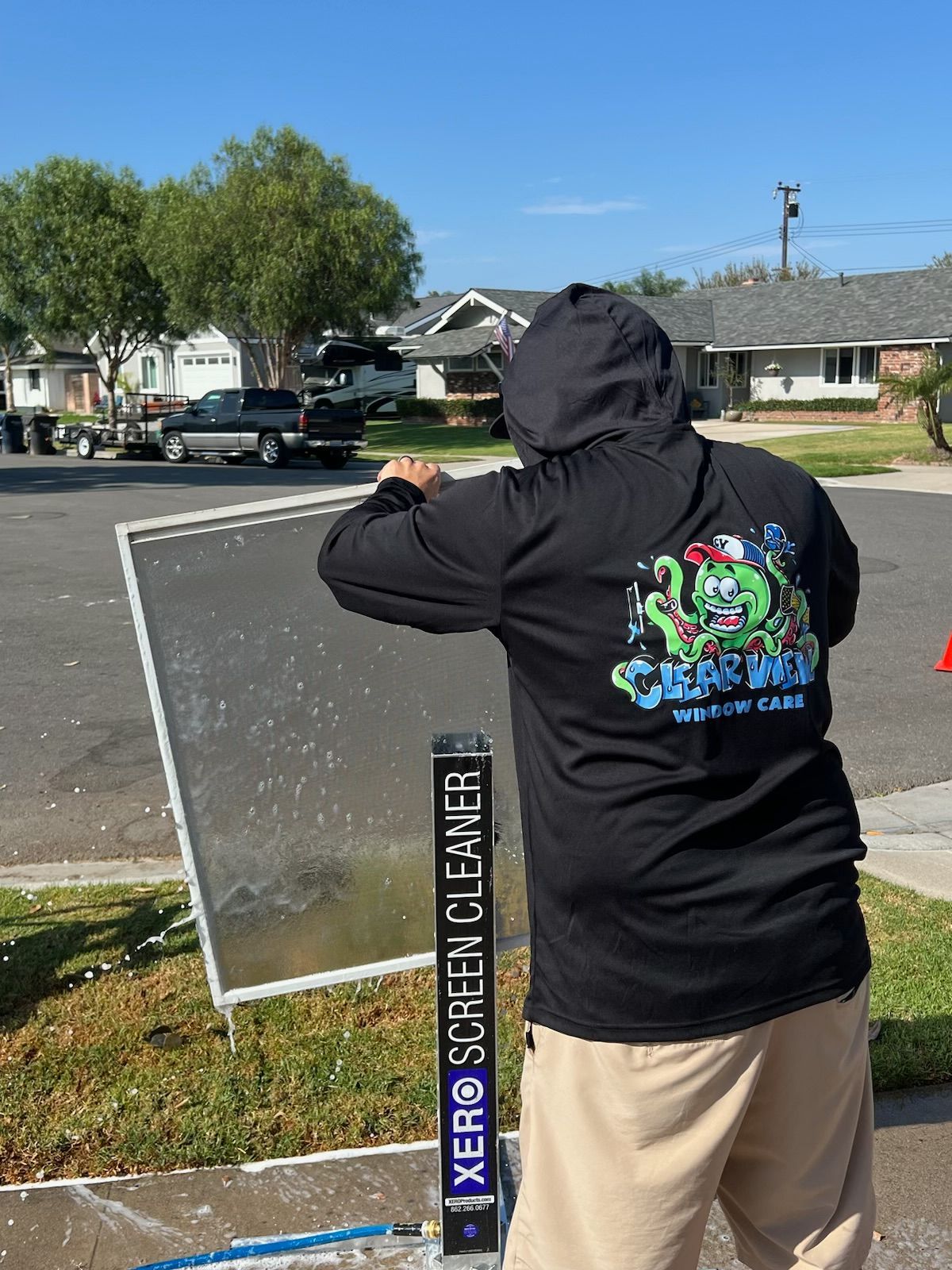 Person in black hoodie standing on a street, holding up a phone near a speed limit sign in a neighborhood