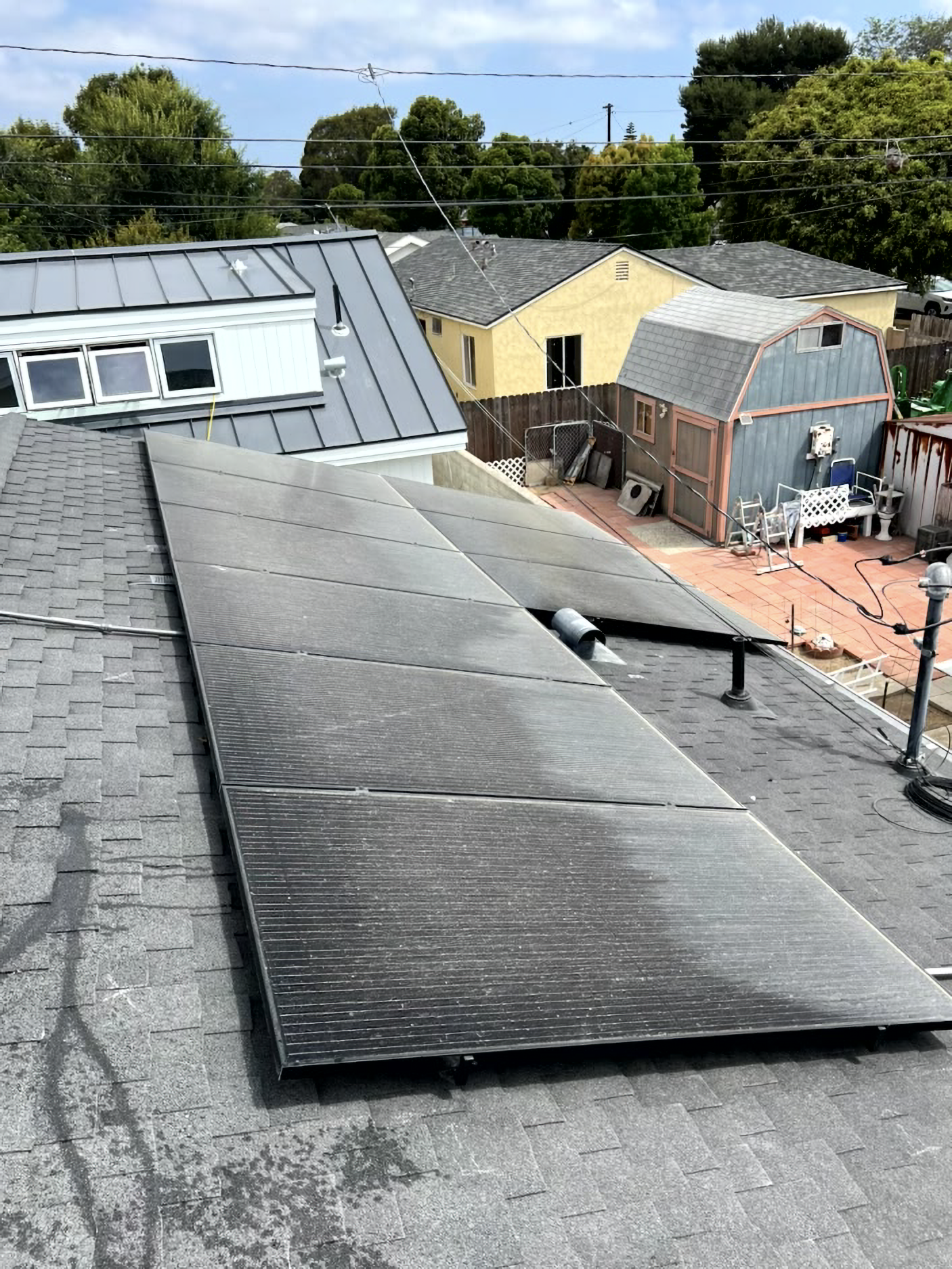 Rooftop with solar panels and a small garden shed under a bright sky