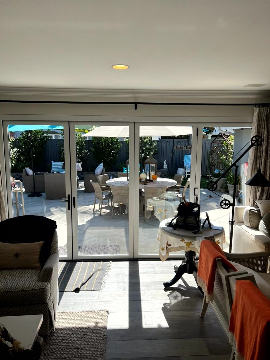 Living room with sliding glass doors opening to a sunny patio and outdoor seating area
