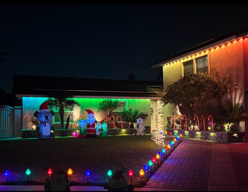 Festive house and yard glowing with colorful Christmas lights at night
