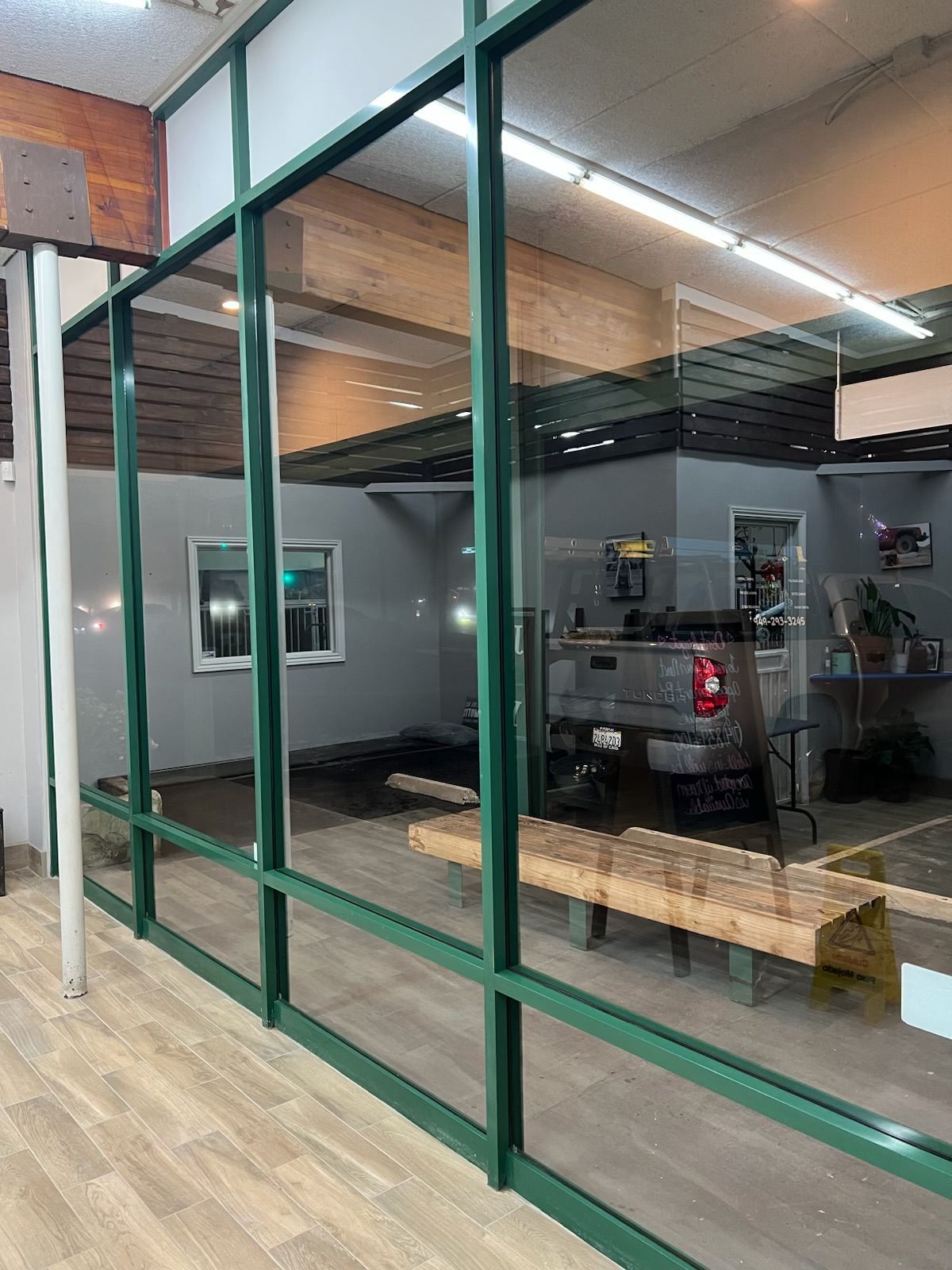 Glass-walled garage with a parked pickup truck inside and a light wood floor outside