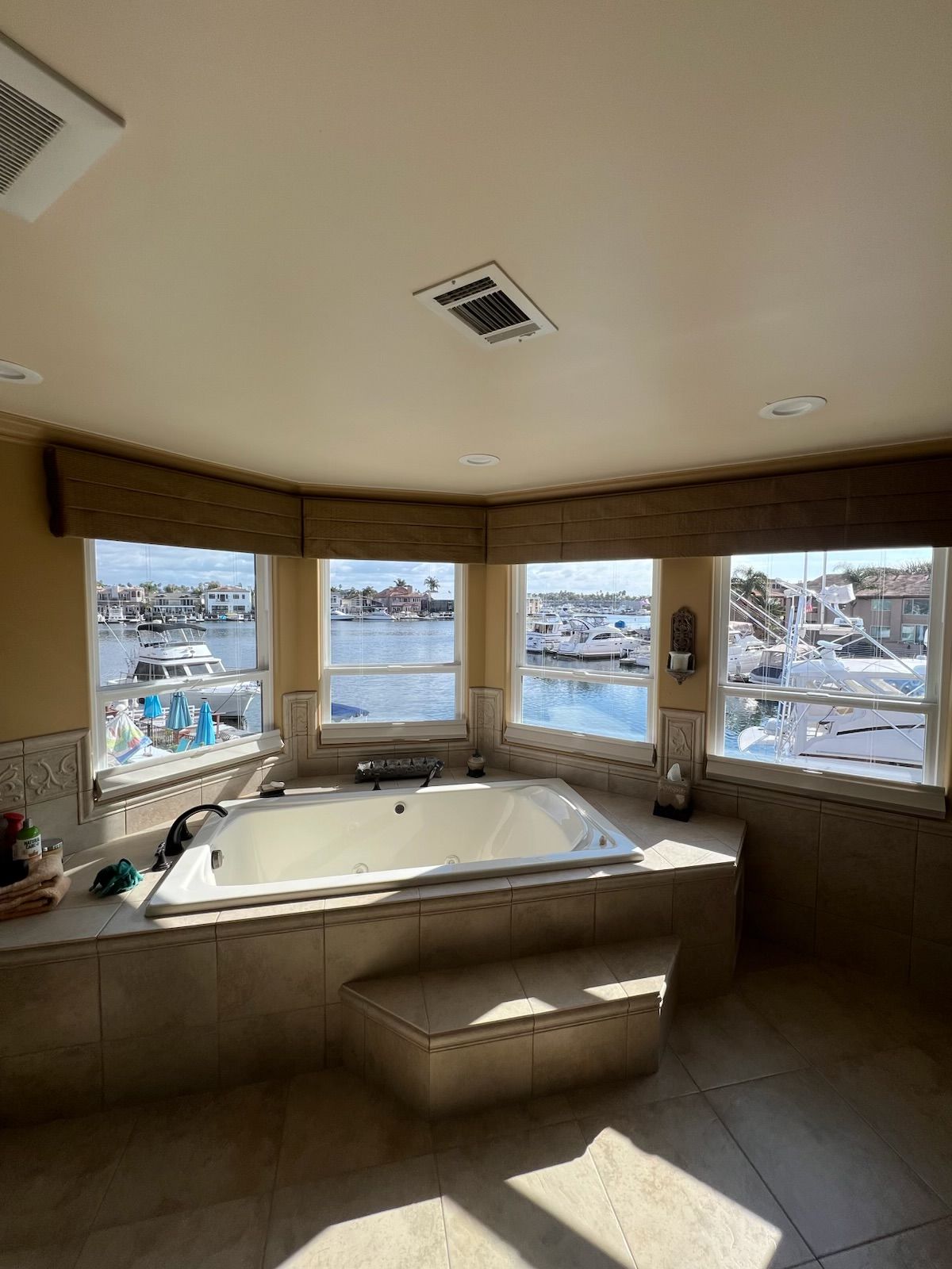 Bright bathroom with corner jacuzzi tub and large windows overlooking a snowy waterfront.
