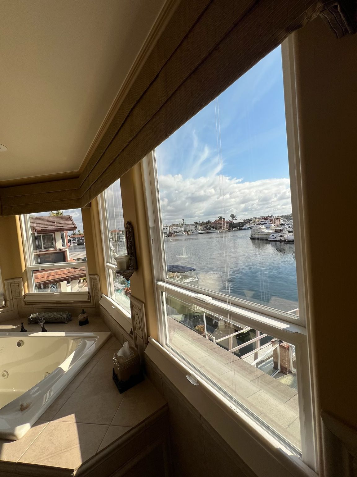 Sunlit harbor view through apartment windows, with a bathtub in the foreground.