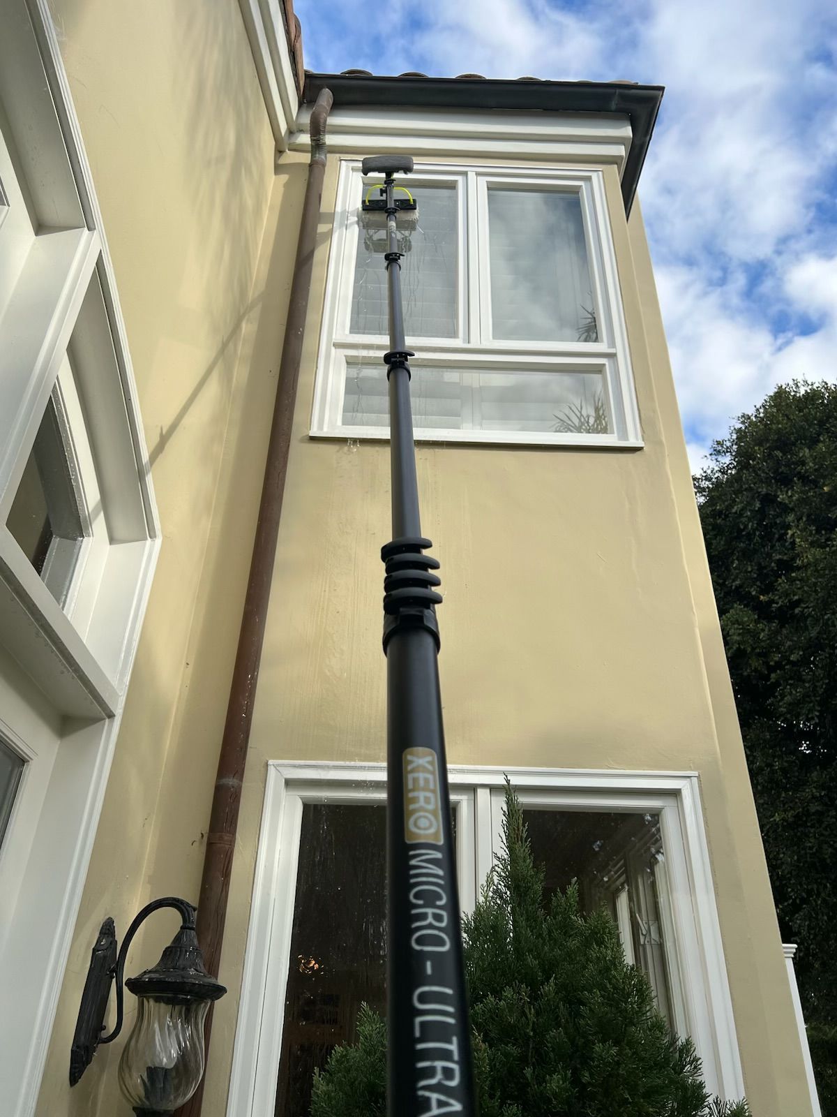 Black streetlamp in front of a cream-colored house with white-trimmed windows and a blue sky above