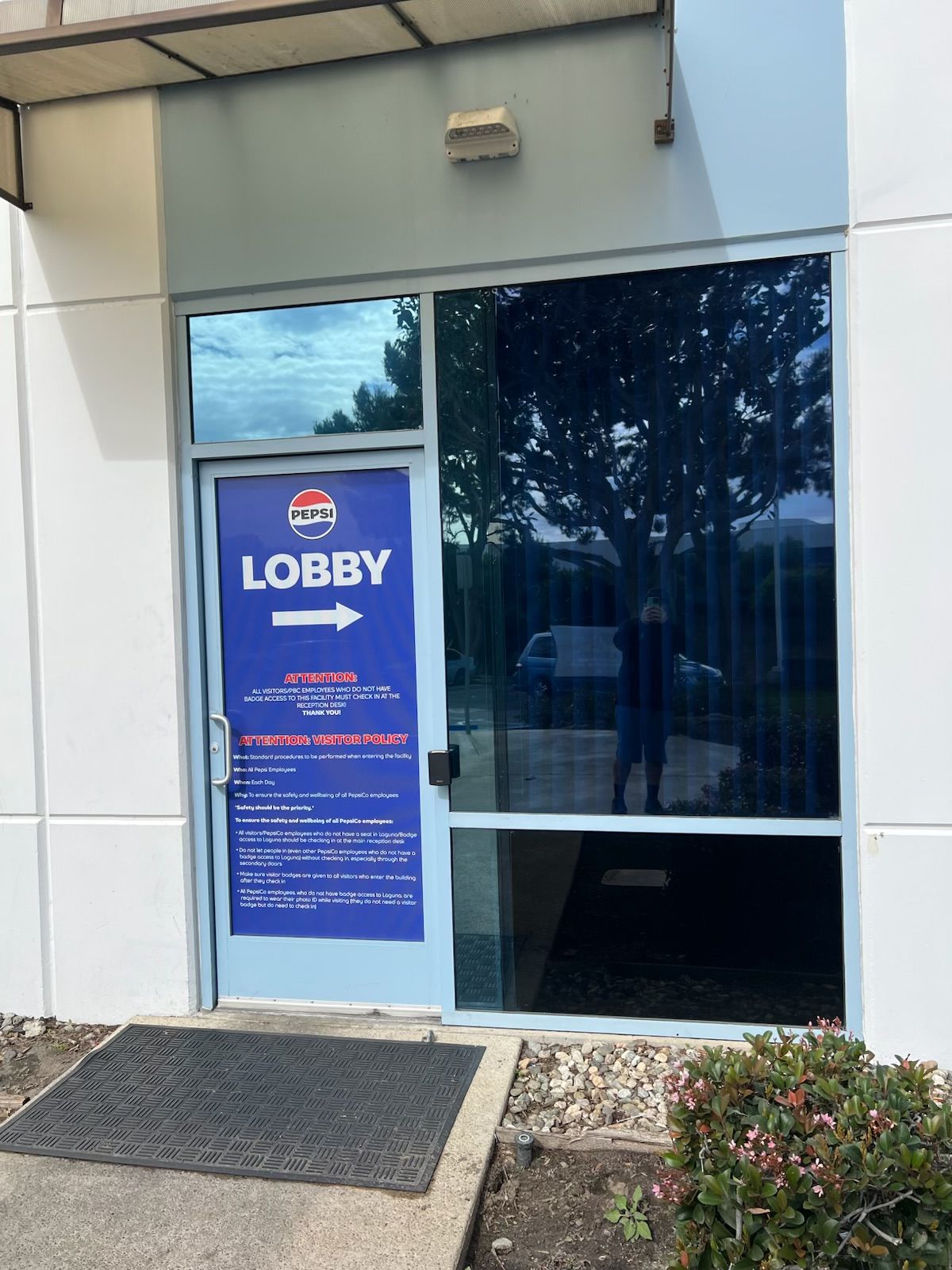 Building entrance with blue “LOBBY” sign beside a glass door.