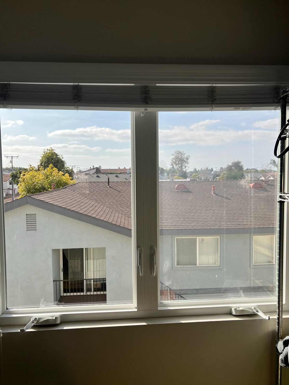 View through a window of rooftops and distant trees on a sunny day