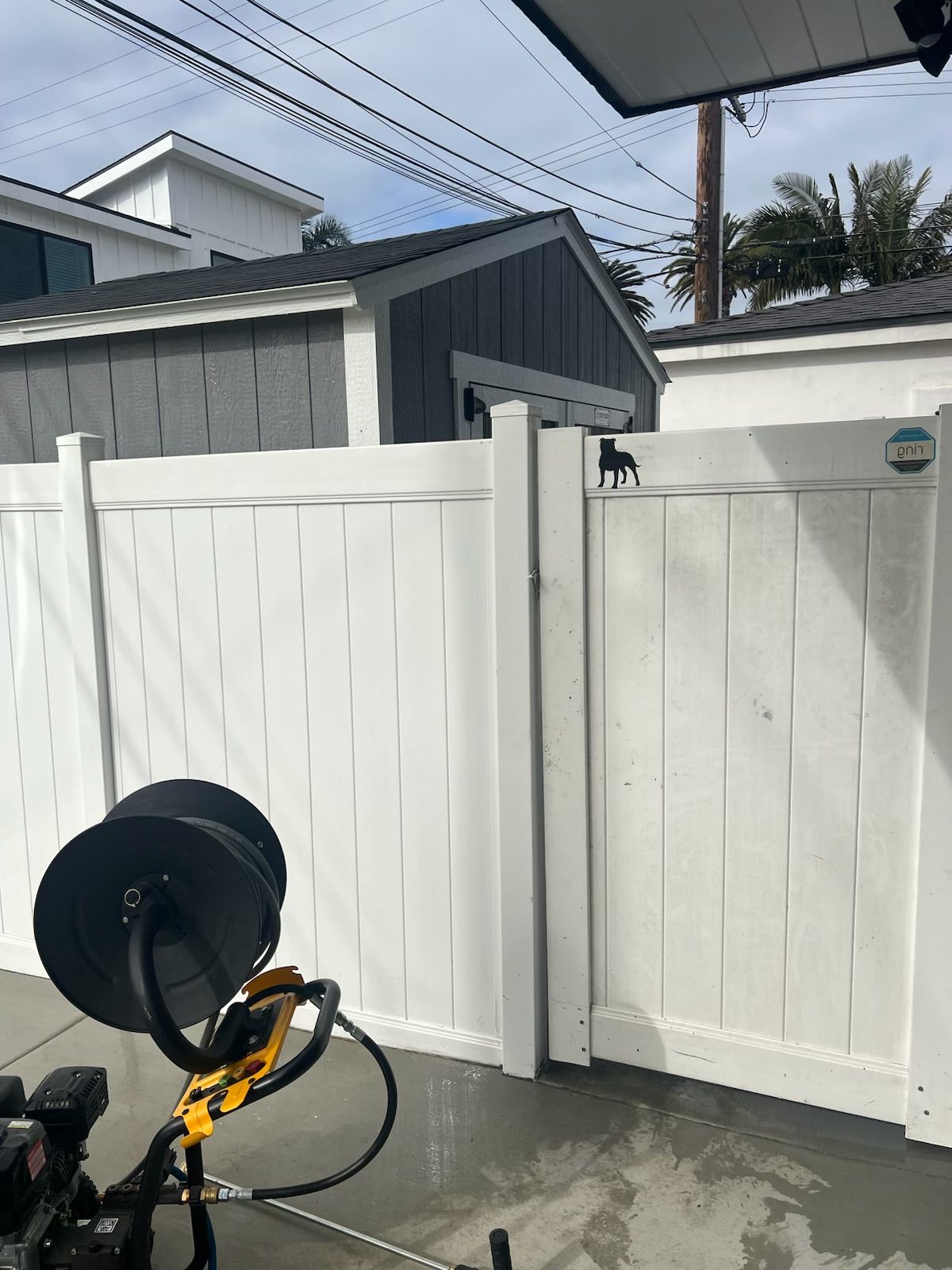 Yellow bicycle with a black rear child seat leaning against a white fence in a driveway.