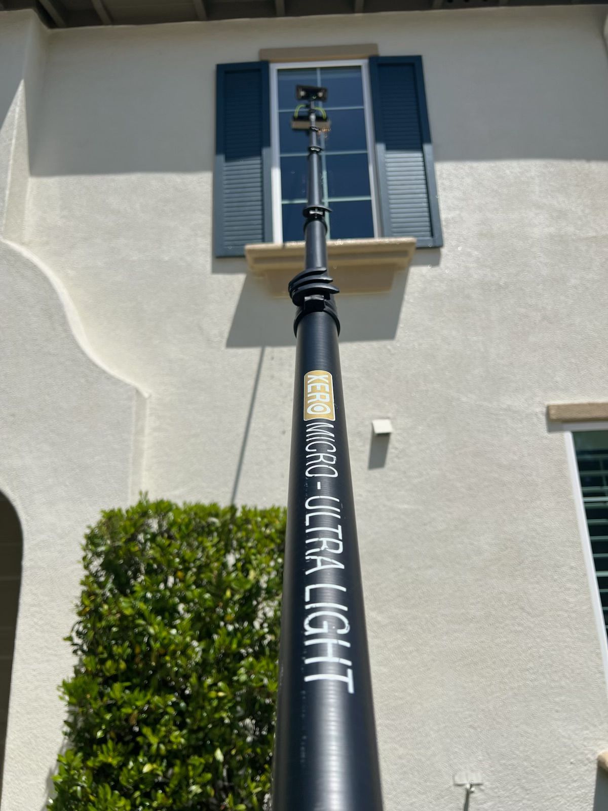 Decorative black street lamp in front of a beige house with blue shutters and a window