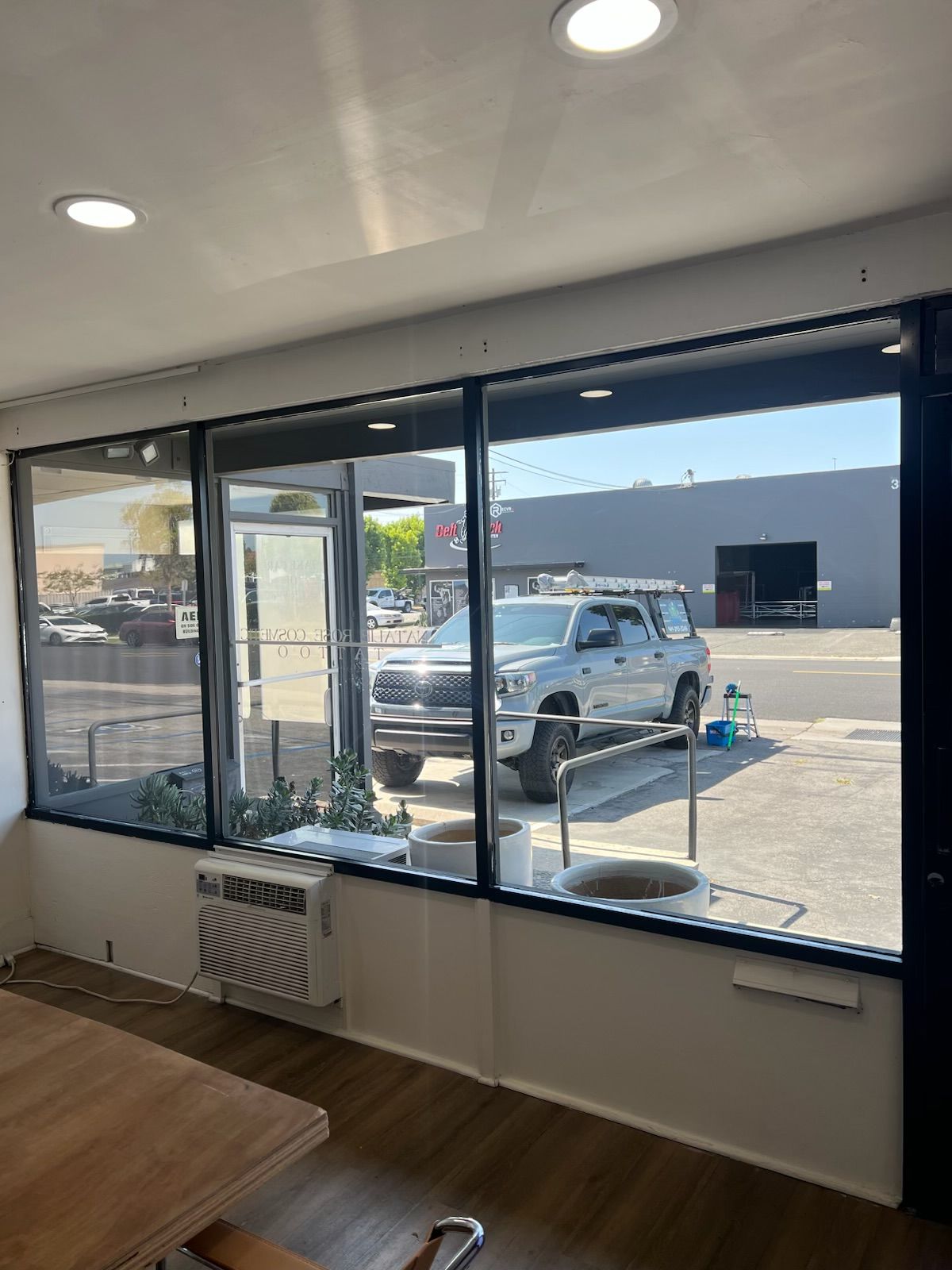Interior view through large windows of a storefront parking lot with a white pickup truck outside