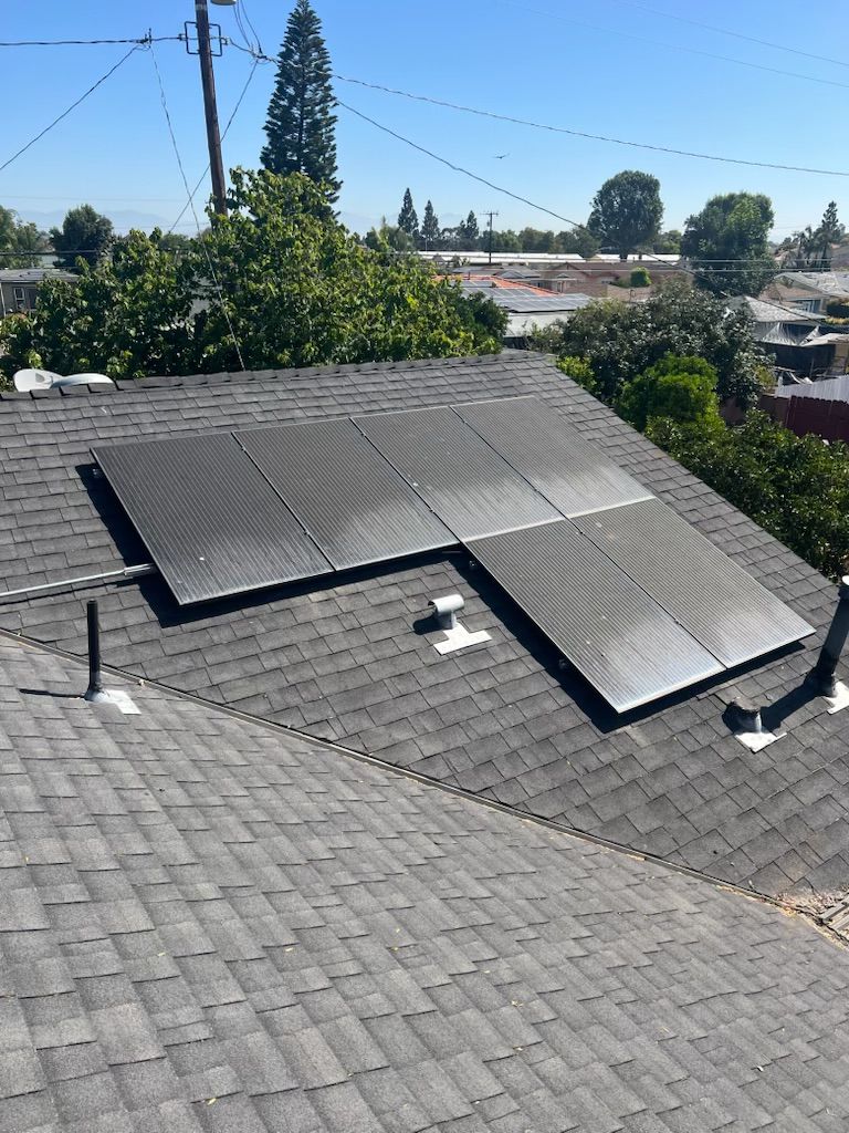 Rooftop solar panels on a shingled house under a clear blue sky