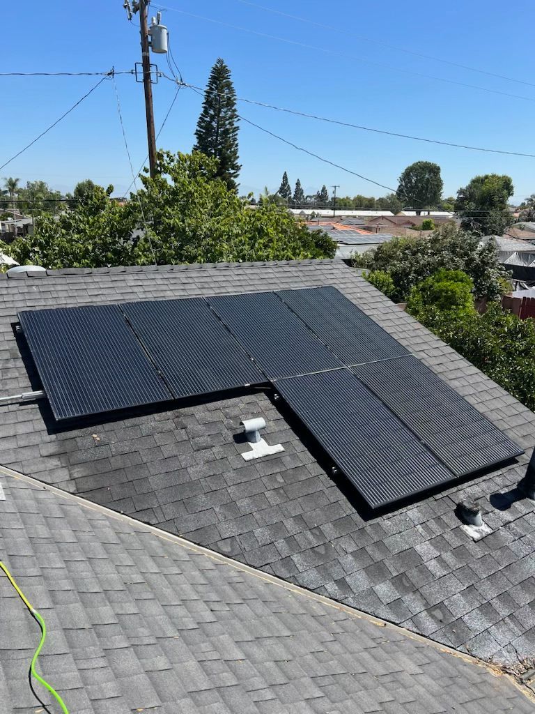 Roof with black solar panels on gray shingles under a clear sky