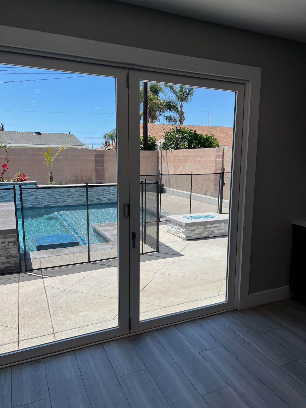 Sliding glass doors open to a backyard with a blue pool, patio, and desert landscaping.